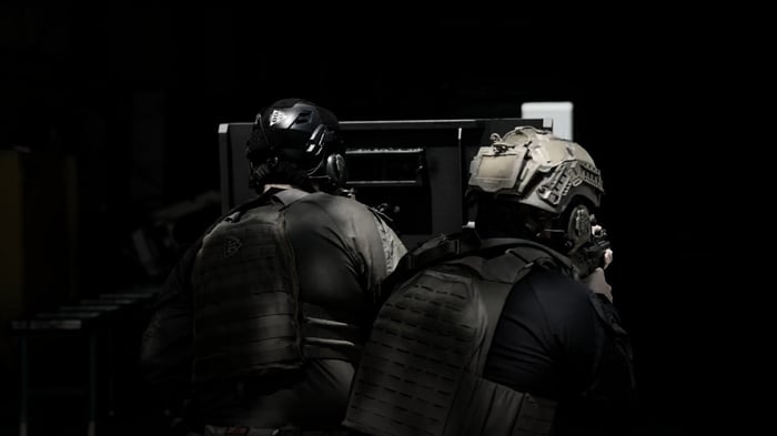 Two SWAT officers using a mobile ballistic shield during a tactical operation for added cover and protection
